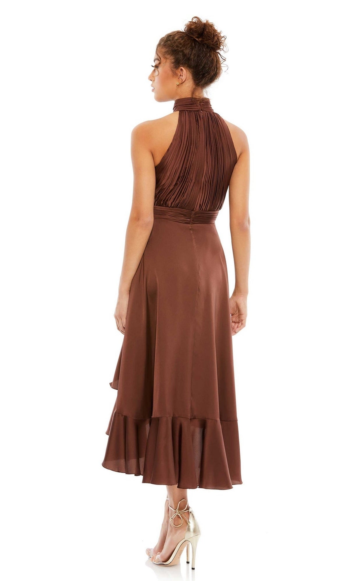A woman stands facing away in the Mac Duggal 49488 High-Low Wedding Guest Dress—sleeveless, brown, with a halter neckline, pleated bodice, and ruffled hem—styled with high-heeled sandals; an ideal tea-length party dress.